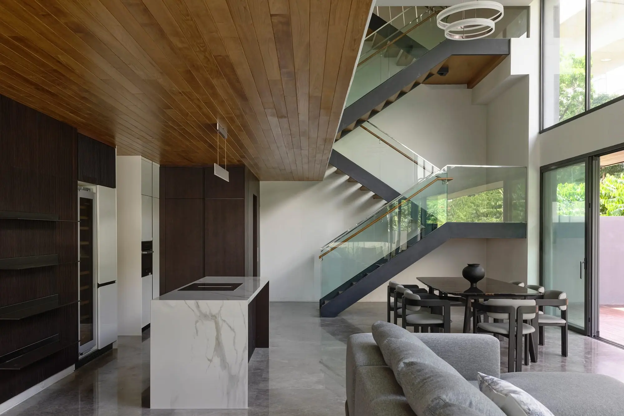 Dining area beside the open stair, lit from a full-height window onto the garden