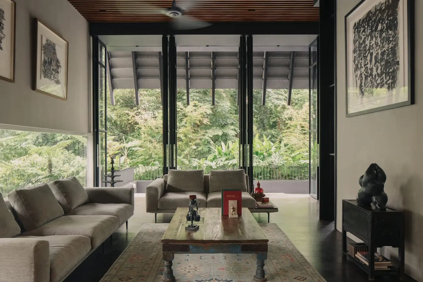 Living room with a timber ceiling and full-height glazing opening onto mature trees