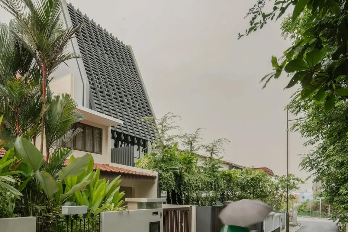 Pitched perforated screen and palms on the street elevation of a Siglap home