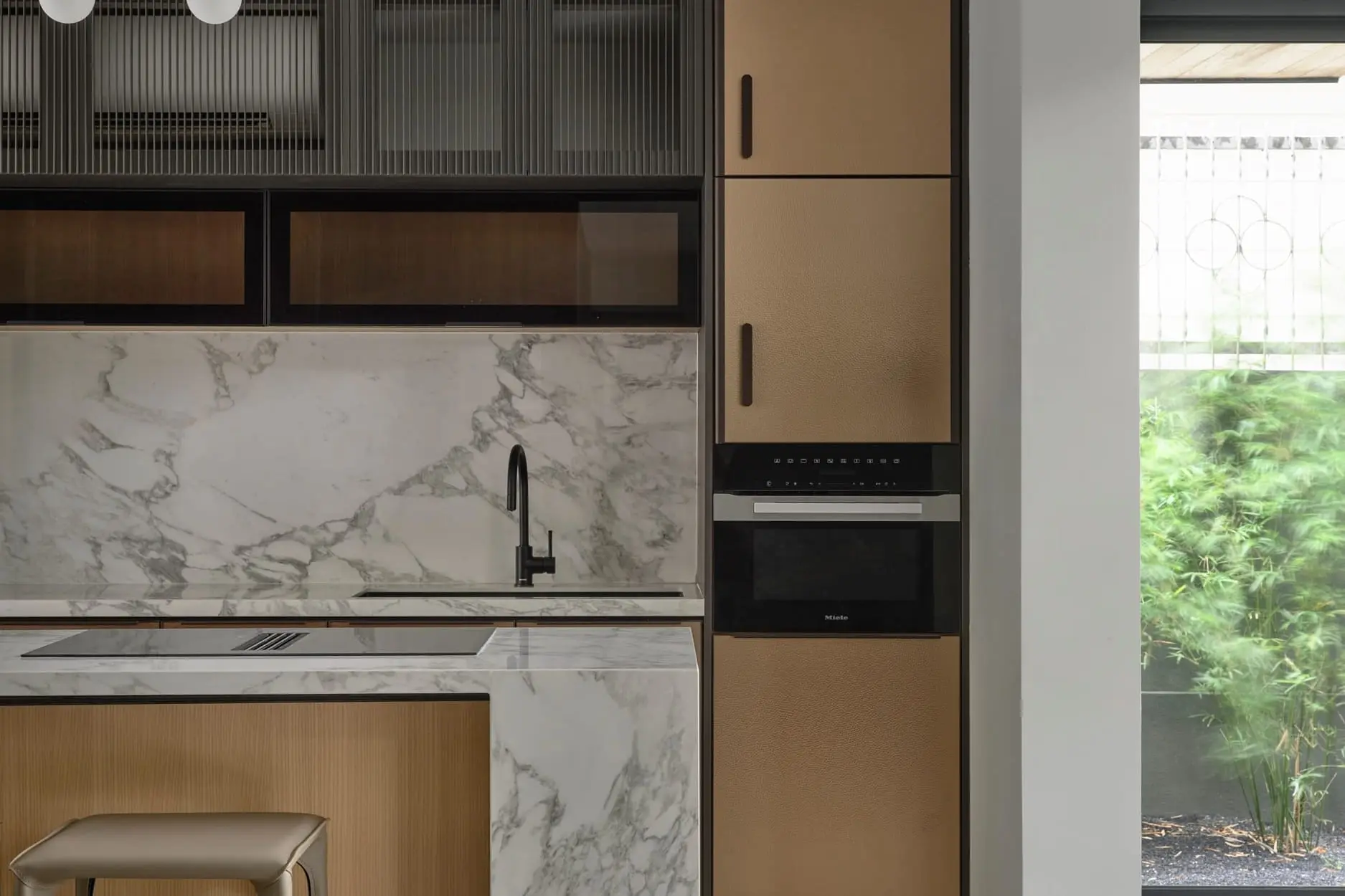 Kitchen with a marble island and backsplash, oak fronts and fluted glass upper cabinets