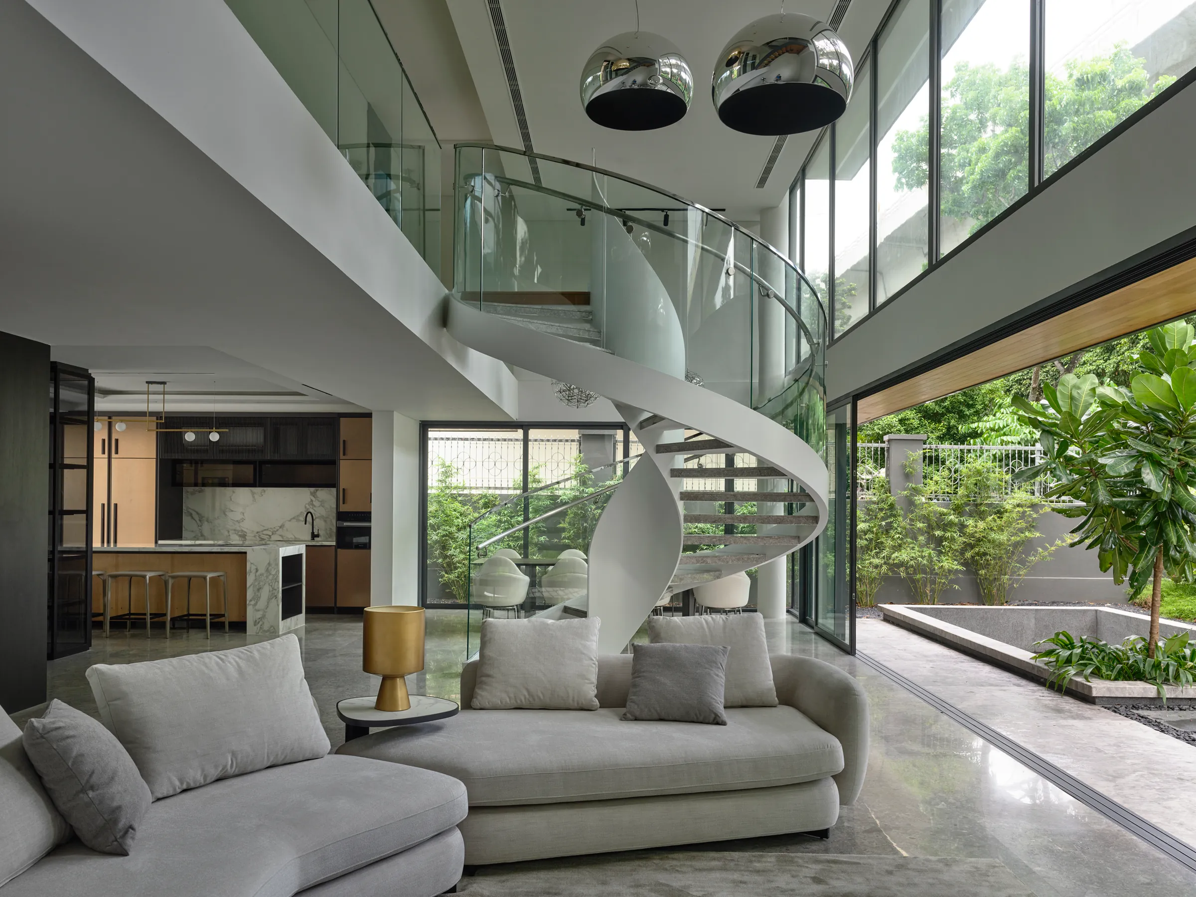 The double-height living room at The Tembusu House, its spiral stair rising toward the light.