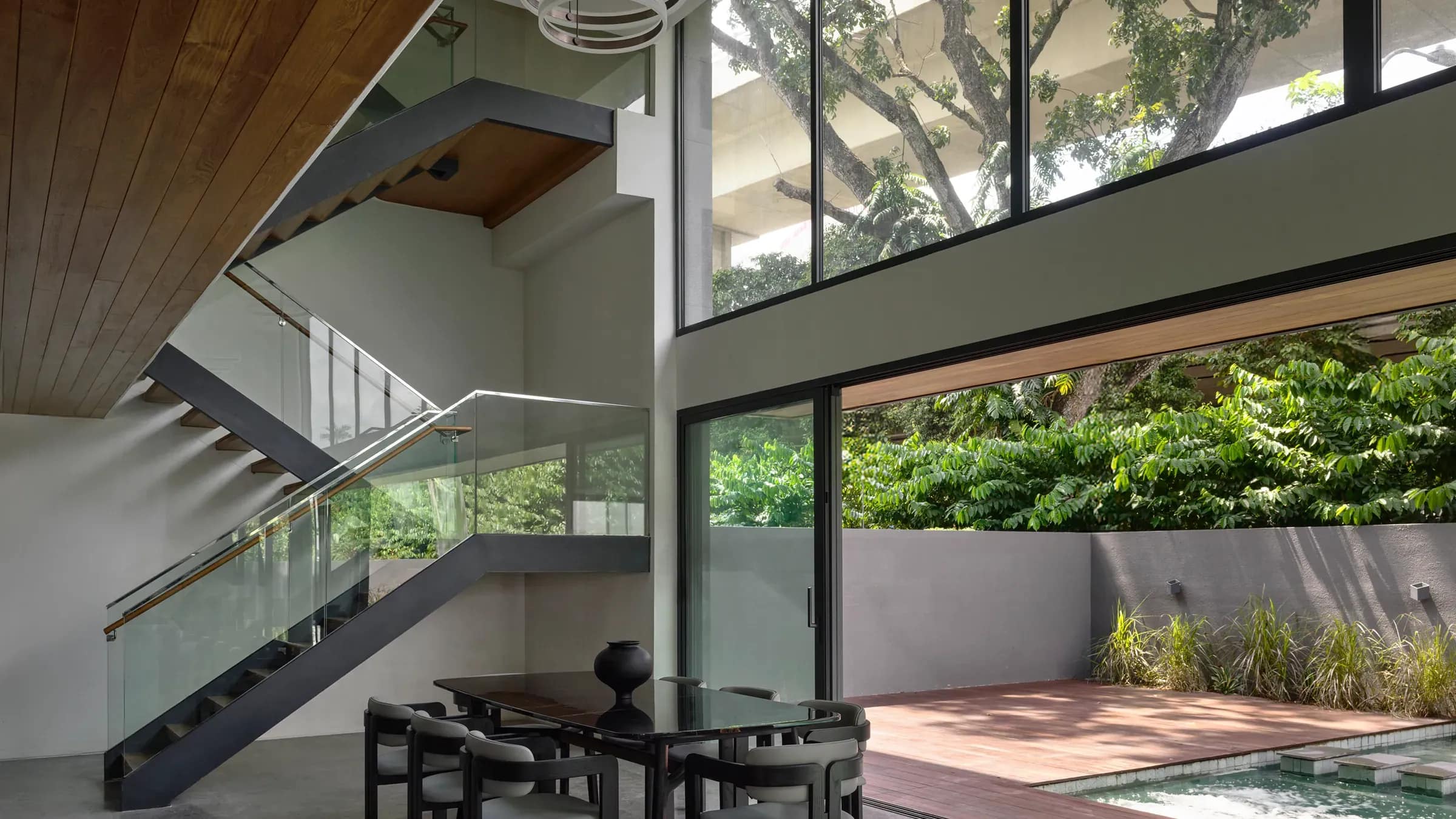 Double-volume dining at The Caspian House, an open-tread stair rising above it.