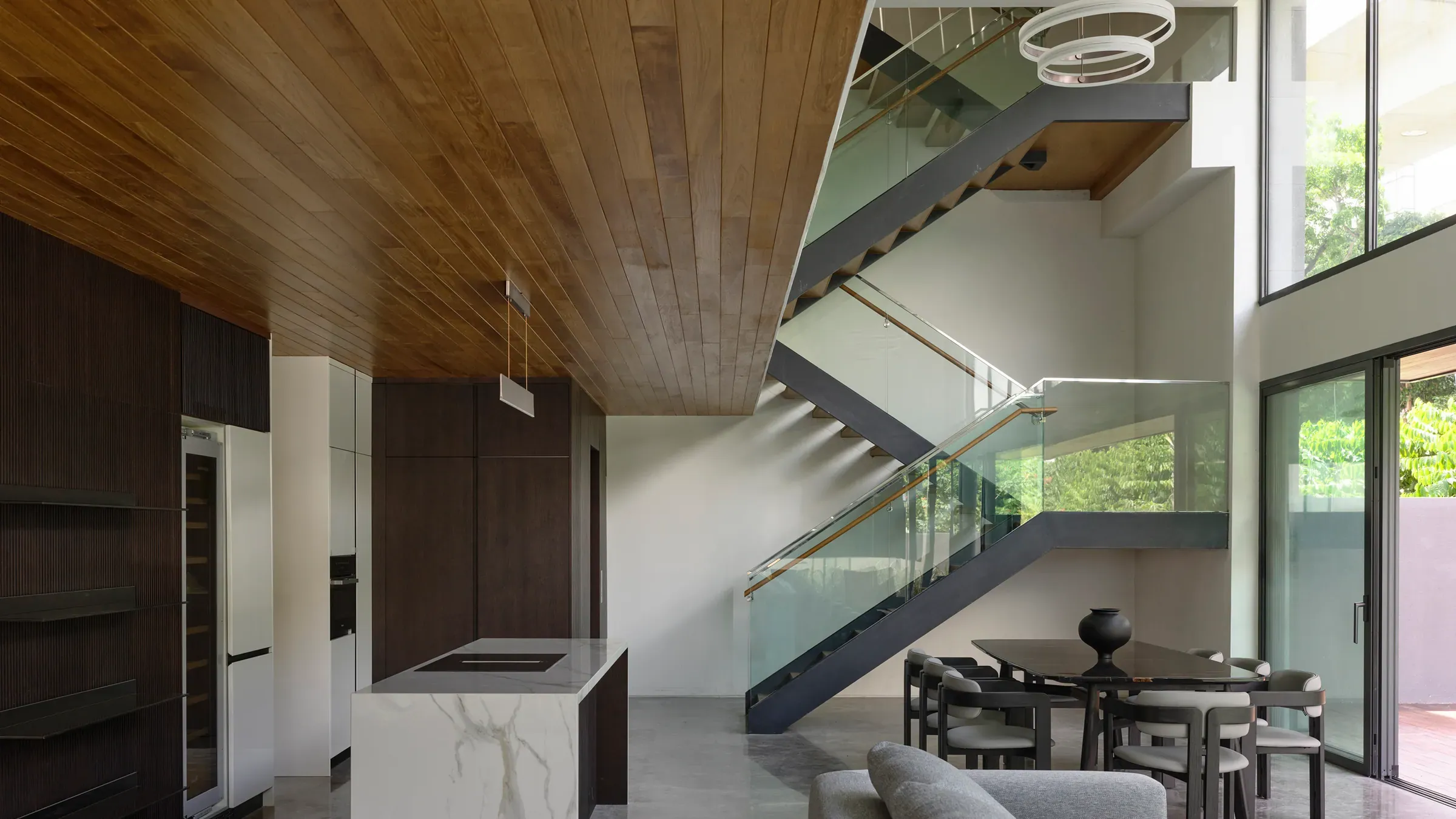 The kitchen at The Caspian House under a timber ceiling, the stair and dining beyond.