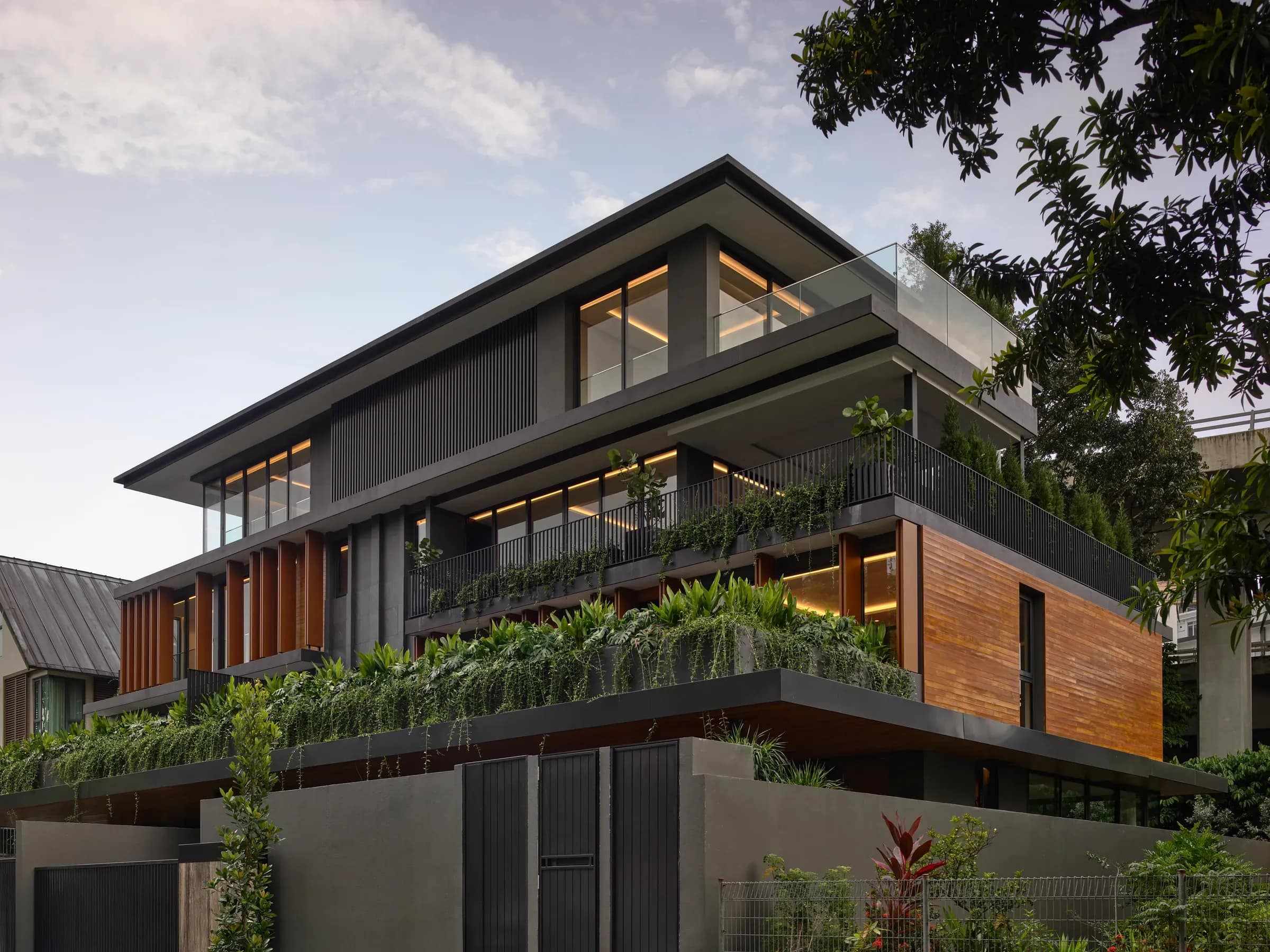 A finished house at Westlake Avenue seen from the street corner, dark cladding and timber over a planted ledge.