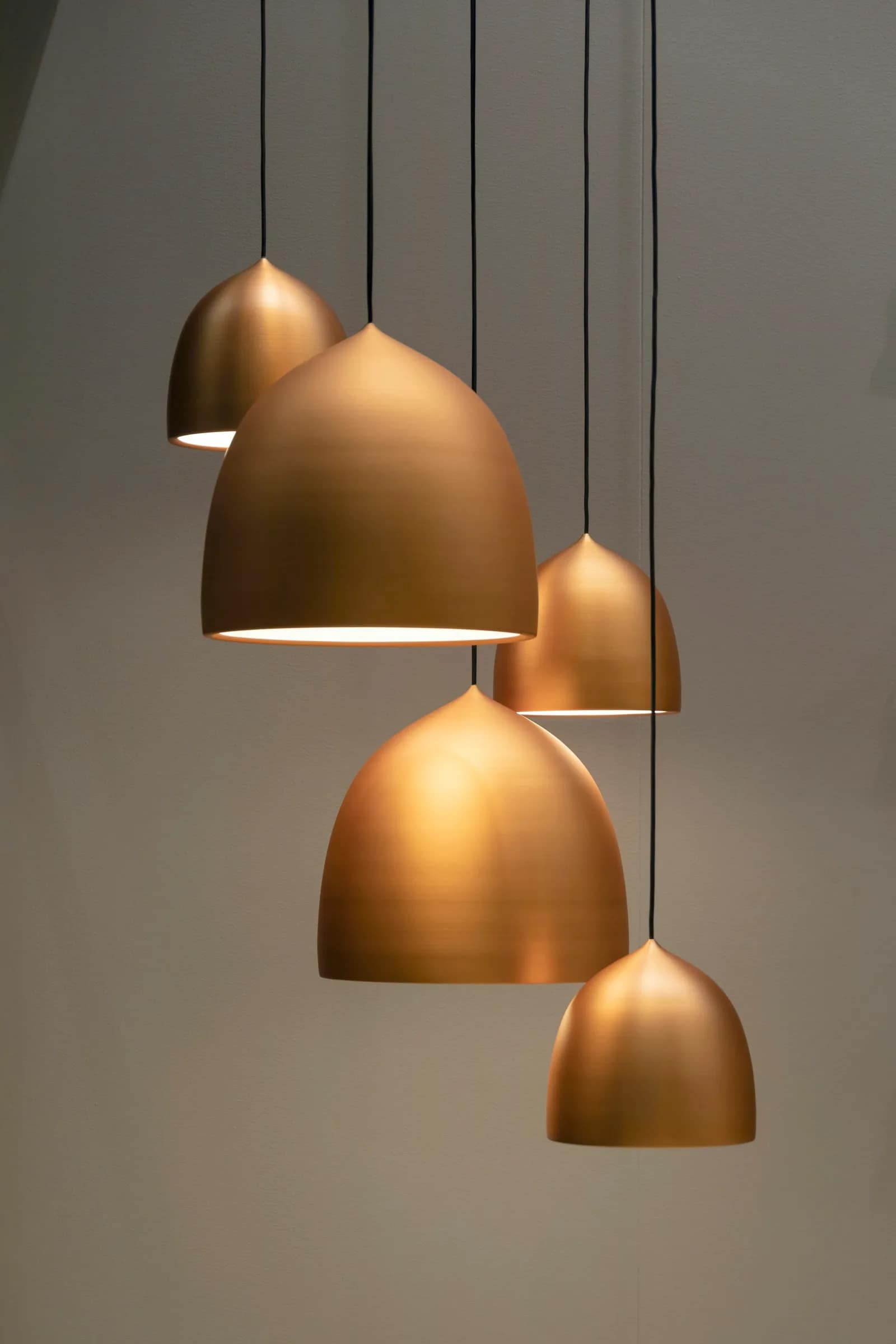 Three brass pendant lights glowing warm against a dark wall.