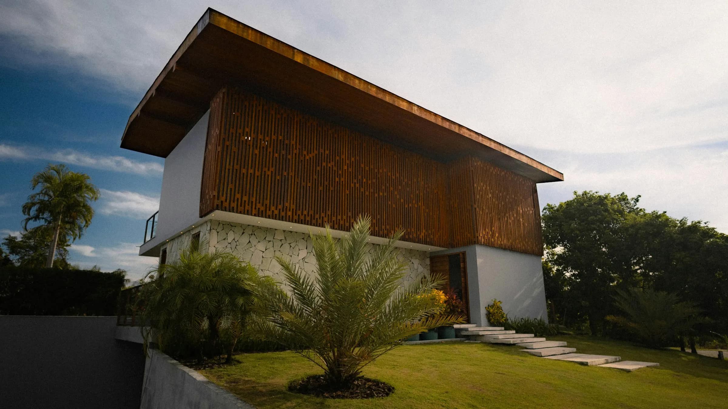 A house whose upper storey is wrapped in timber screening under a deep, overhanging roof.